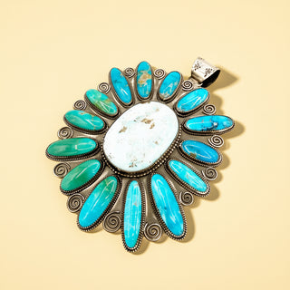 Pendant with turquoise stones and a white center on a beige background