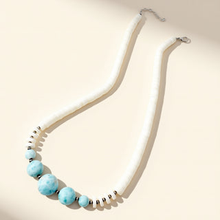 Necklace with white beads and blue accents on a beige background