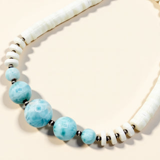 Necklace with turquoise beads and white shell elements on a beige background