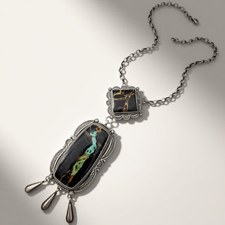 Silver necklace with black and silver pendant on a light gray background