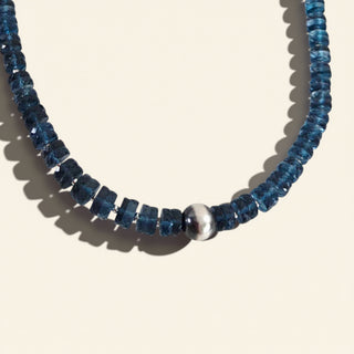 Necklace with blue beads and a silver clasp on a beige background
