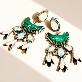 Green earrings against a beige background