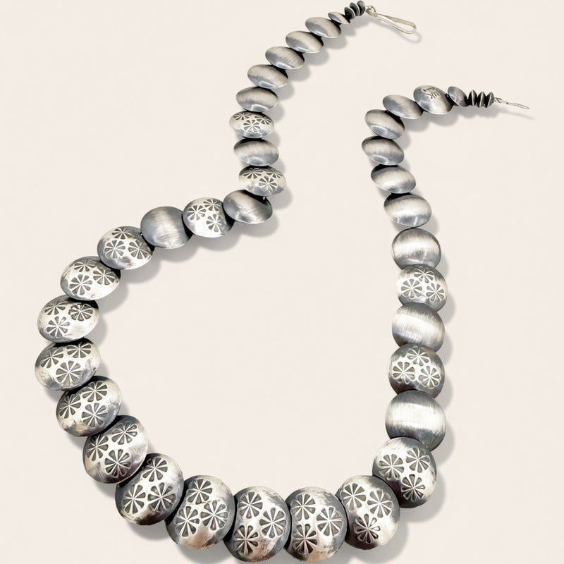 Silver beaded necklace on a light beige background