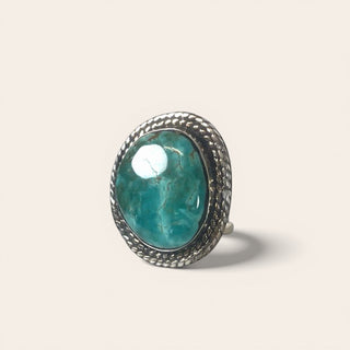 Ring with a turquoise stone and silver band on a light beige background