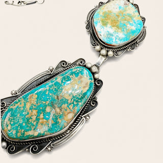 Turquoise stone earrings with silver detailing on a beige background