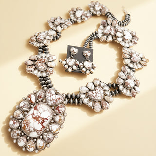 Silver jewelry set with necklace and earrings on a beige background