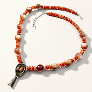 orange beaded necklace with pendant on a beige background