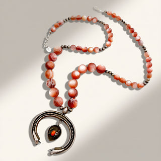 orange beaded necklace with pendant on a beige background