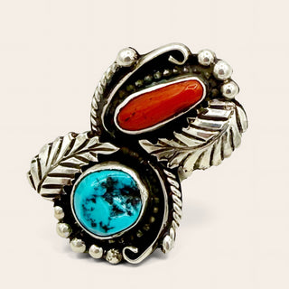 Silver ring with red and turquoise stone on a beige background