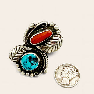 Silver jewelry with turquoise and coral next to a quarter for scale on a white background