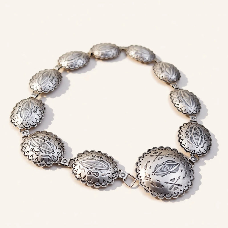 A silver-toned concho-style bracelet with multiple oval links displayed on a clean off-white background.