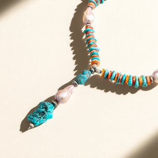 Necklace with turquoise stones and pearls on a beige background