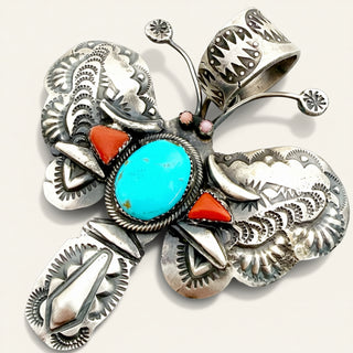Silver butterfly pendant with turquoise and red stones on a white background