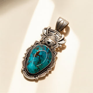 Silver pendant with turquoise stone on a beige background