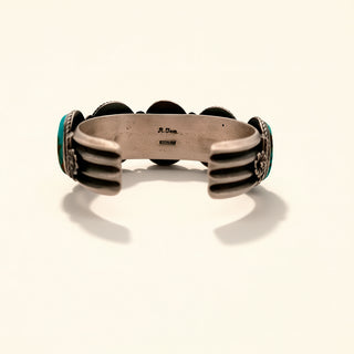 Bracelet with metallic band and turquoise accents on a beige background