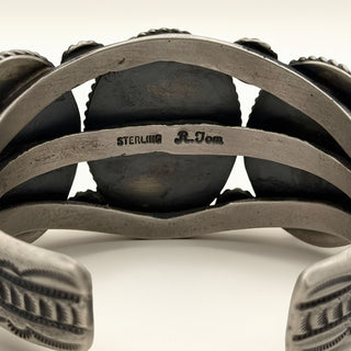 Close-up of a silver bracelet with engraved text on a neutral background