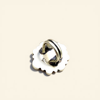 Silver ring with scalloped edge on a beige background