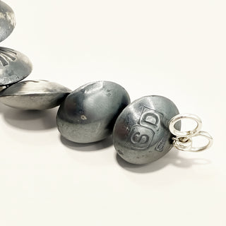 Close-up of metallic beads with a visible brand logo on a white background