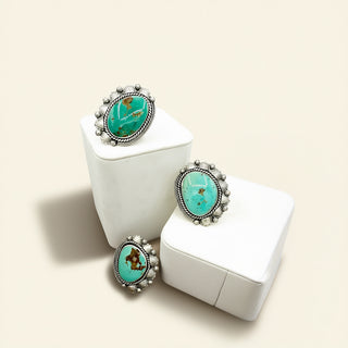 Three silver rings with turquoise stones on a beige background