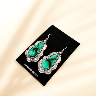 Pair of turquoise earrings on a black card with 'Sterling Silver' text, set against a beige background.