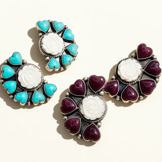 Pair of earrings with turquoise and purple heart designs on a white background