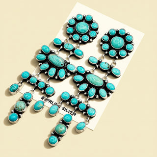 Turquoise and silver earrings on a beige background