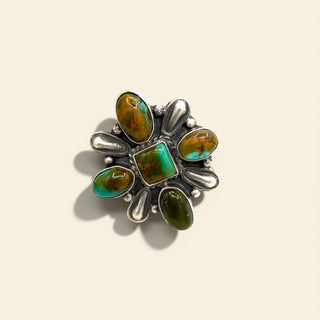 Silver ring with green and brown gemstones on a beige background