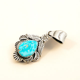 Turquoise stone pendant with silver decorative elements on a white background