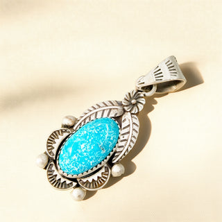 Silver pendant with a blue stone on a beige background