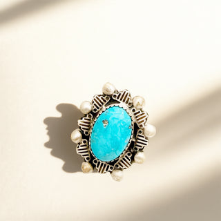 Jewelry with turquoise stone and pearl accents on a beige background