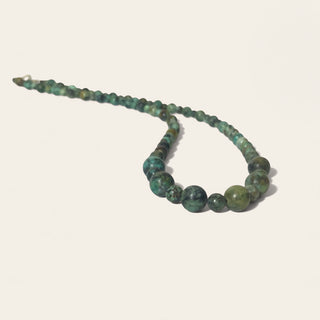 Green beaded necklace on a white background
