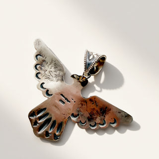 A sterling silver pendant with intricate cutouts and engraved details, displayed on a clean white background with a soft shadow.