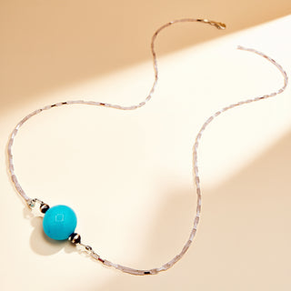 Necklace with a turquoise bead on a beige background
