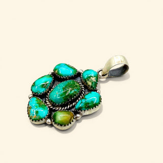 Turquoise pendant with silver setting on a beige background