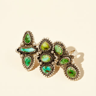 Three silver rings with green stones on a beige background