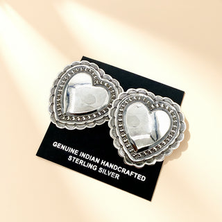 Silver heart earrings on a beige background