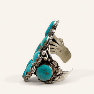A wide sterling silver cuff ring featuring multiple round turquoise cabochons, photographed on a clean off-white background.