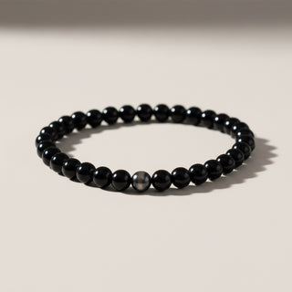 Black beaded bracelet on a light beige background