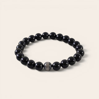 Black beaded bracelet on a light beige background