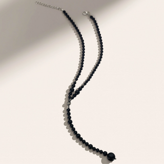Black beaded necklace on a light gray background