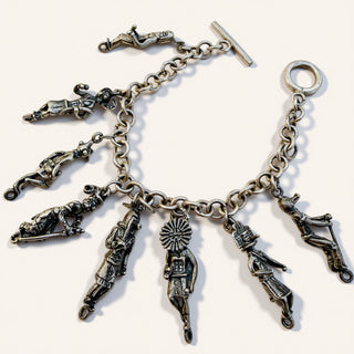 Silver charm bracelet with various charms on a white background