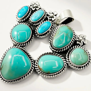 A sterling silver multi-stone pendant featuring seven turquoise-colored cabochon gemstones in a traditional Southwestern style, set against a clean white background.