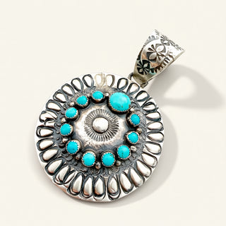 silver pendant with turquoise stones on a beige background