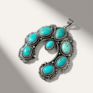 A silver-toned Southwestern-style pendant necklace featuring seven oval turquoise stones set in ornate filigree and rope-textured silver settings, displayed on a light gray background with soft diagonal shadows.