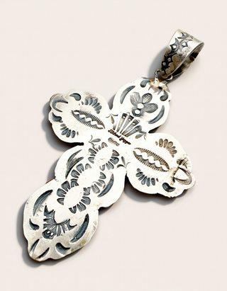 The back of a silver cross pendant stamped and showing the name Richard Yazza