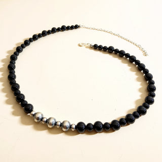 Necklace with black beads and silver accents on a white background