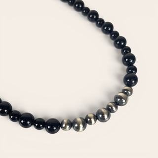Necklace with alternating black and silver beads on a light gray background