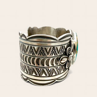 silver cuff with intricate patterns on a beige background