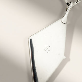 Close-up of a silver pendant on a light gray background