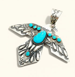 Silver Bird Pendant with Turquoise stones on a cream background